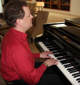Mann spielt Klavier. Pianist in rotem Hemd am Flügel. Musik und Unterhaltung.