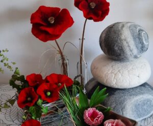 Dekorative rote Mohnblumen, Filzsteine und Blumenarrangements als Tischdeko.