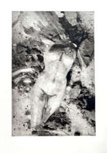 Schwarz-Weiß-Foto: Torso einer antiken Statue, umgeben von Steinen und Schmutz. Archäologie Kunst.