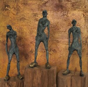 Skulpturen bei der Kulturnacht Radolfzell: Drei Bronzefiguren auf Holzsockeln vor goldenem Hintergrund. Kunstausstellung.