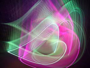 Abstrakte Kunst: Pinke und grüne Lichtspuren erzeugen dynamische, leuchtende Formen auf dunklem Hintergrund.