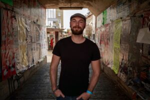 Mann mit Bart und Mütze in Unterführung. Streetart und urbane Atmosphäre. Porträt im Freien.