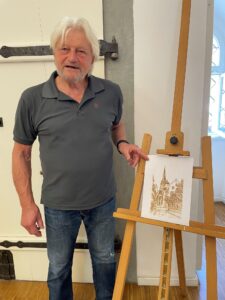 Künstler präsentiert Zeichnung einer Kirche auf Staffelei. Kunstausstellung.
