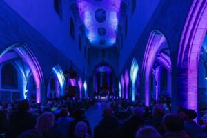 Kirche Innenraum: Blaue Beleuchtung, Menschenmenge. Architektur und Lichtdesign in historischer Kirche.