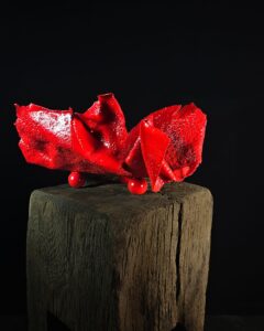Rote Skulptur auf Holzsockel. Moderne Kunst, abstraktes Design. Dekorative Kunst.