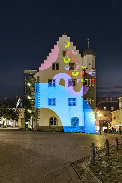 Illuminiertes Rathaus bei Nacht. Farbenfrohe Projektionen auf historischem Gebäude. Stadtbild mit Lichtkunst.