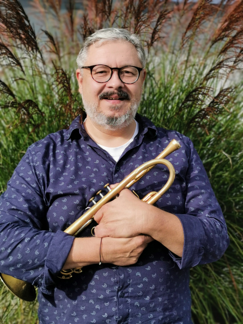 Mann mit Trompete. Musiker mit Brille und Bart hält goldene Trompete. Musikinstrument.