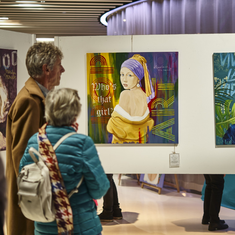Besucher betrachten Gemälde in einer Kunstausstellung. Kunstwerk mit Mädchen mit dem Perlenohrring-Motiv.