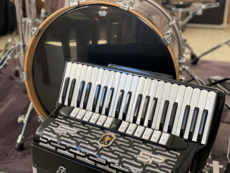 Akkordeon und Schlagzeug: Musikinstrumente im Studio. Schwarzes Akkordeon vor großem Schlagzeug. Musikzubehör.