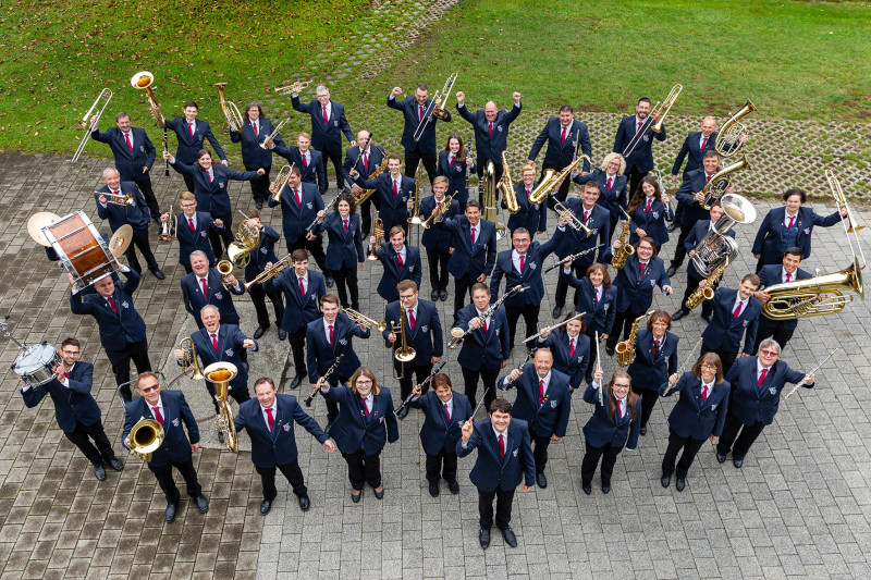 Großes Blasorchester in Uniform mit Instrumenten, aufgenommen von oben. Musikverein, Blasmusik, Orchester.