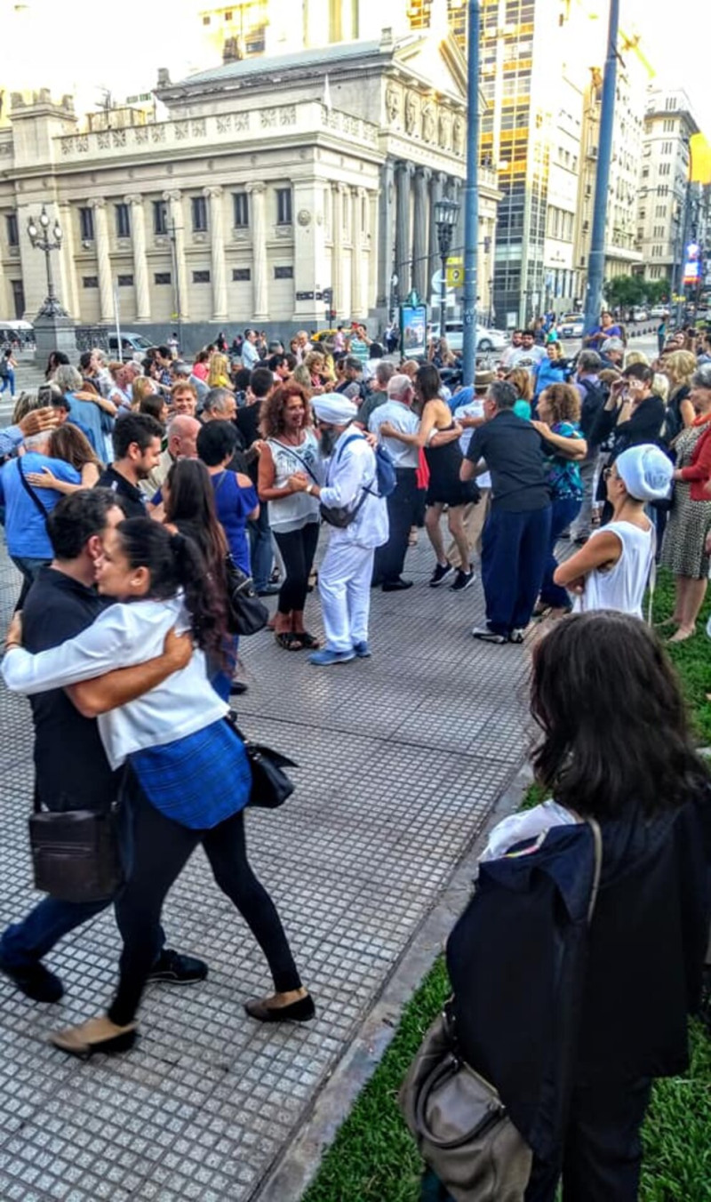 Tango tanzen in Buenos Aires: Menschen umarmen sich auf der Straße vor historischer Architektur.