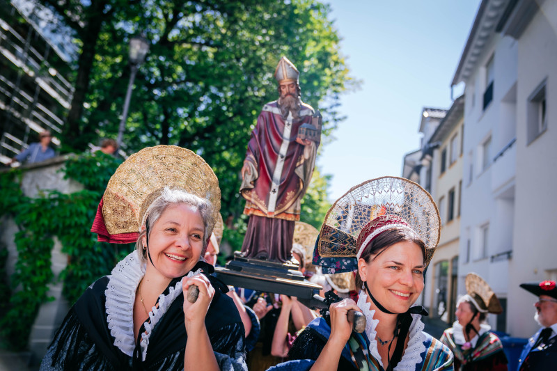 Trachtenfrauen tragen Statue bei Prozession. Traditionelle Kleidung und Brauchtum in der Schweiz.